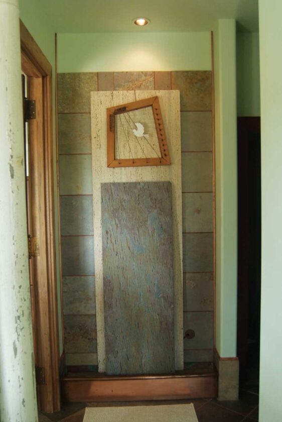 Inside one of the home's entraces, a slate waterfall features an antique harp and peace dove.